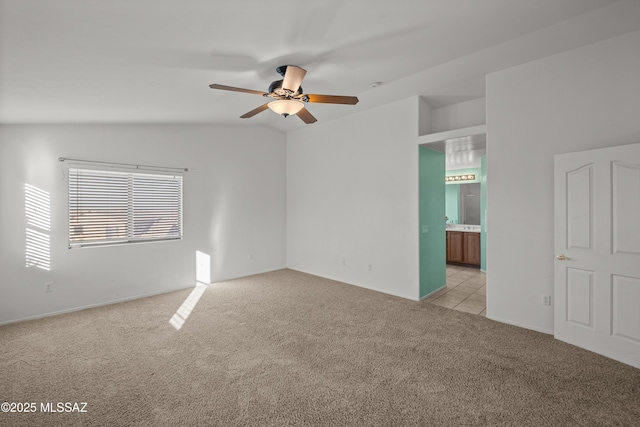 carpeted spare room with ceiling fan and vaulted ceiling