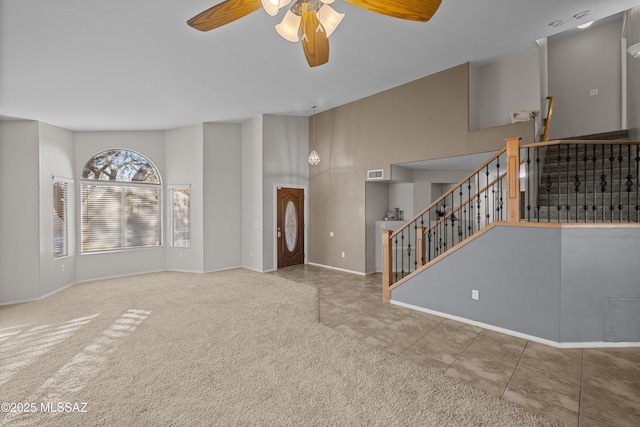 unfurnished living room featuring ceiling fan, carpet, and a high ceiling