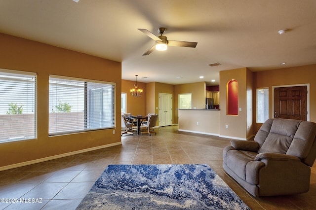 living room featuring tile patterned flooring and ceiling fan with notable chandelier