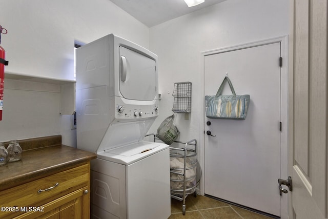 washroom featuring stacked washer and dryer, cabinets, and dark tile patterned floors