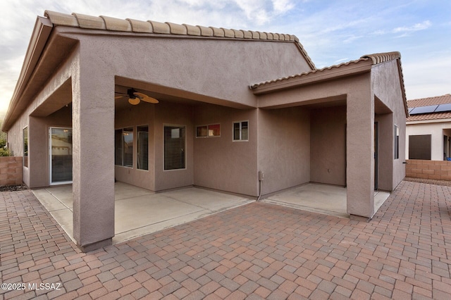 back of property with ceiling fan and a patio area