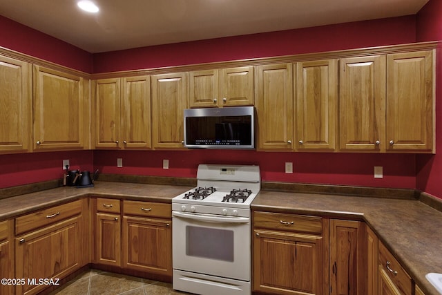 kitchen with light tile patterned floors and white gas stove