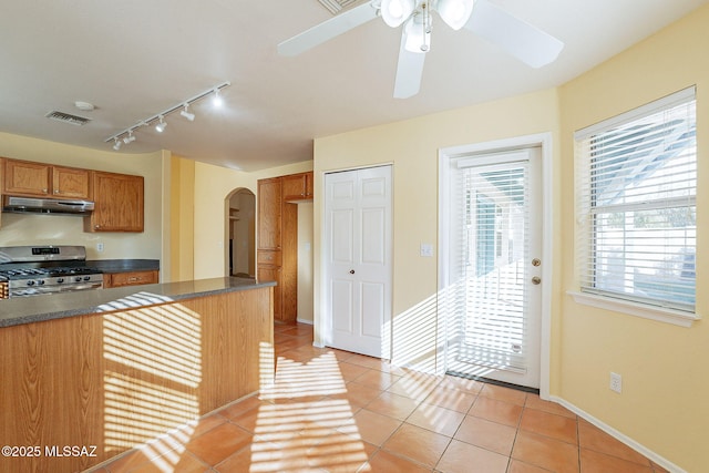 kitchen with gas range, rail lighting, ceiling fan, and light tile patterned flooring