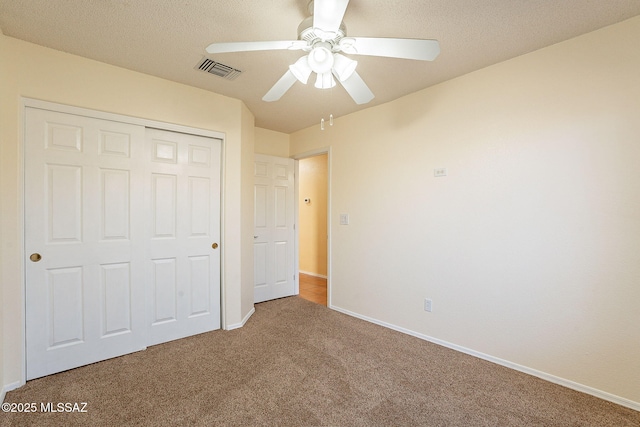 unfurnished bedroom featuring ceiling fan, carpet flooring, a closet, and a textured ceiling