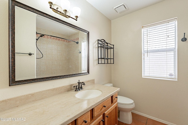 bathroom featuring vanity, toilet, tile patterned flooring, and a tile shower