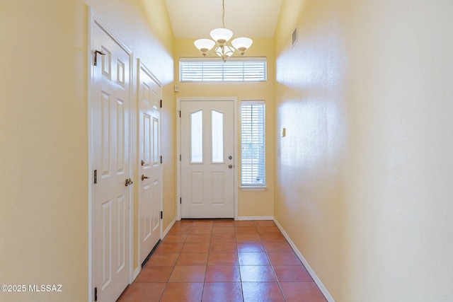 entryway with tile patterned flooring, a towering ceiling, and a chandelier