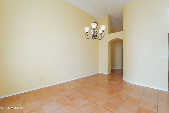 empty room with an inviting chandelier, light tile patterned floors, and high vaulted ceiling