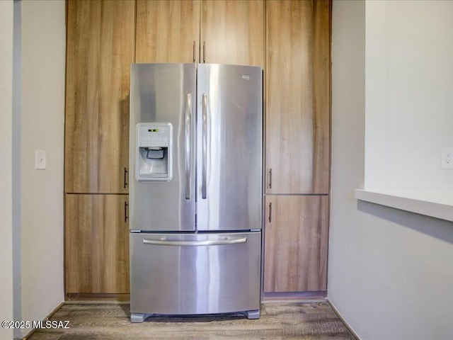 kitchen with hardwood / wood-style flooring, light brown cabinets, and stainless steel fridge