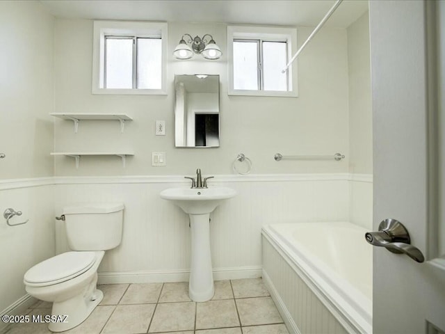 bathroom featuring a washtub, toilet, tile patterned floors, and plenty of natural light