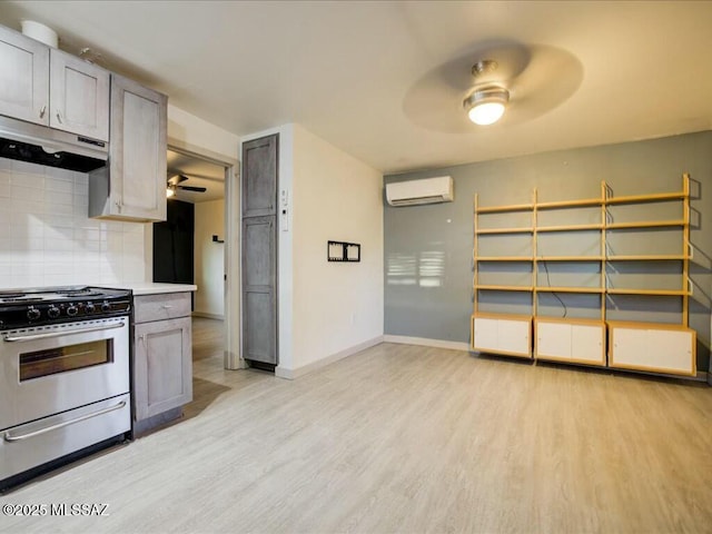 kitchen with an AC wall unit, tasteful backsplash, light wood-type flooring, ceiling fan, and electric range