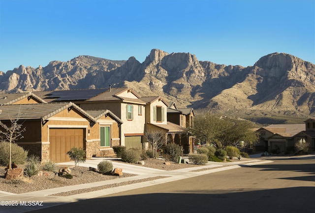 view of front of property with a garage, a mountain view, and solar panels