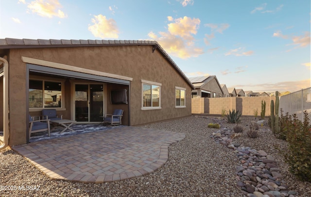 back house at dusk featuring a patio