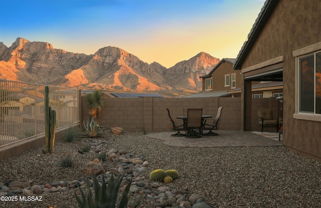 yard at dusk featuring a mountain view and a patio