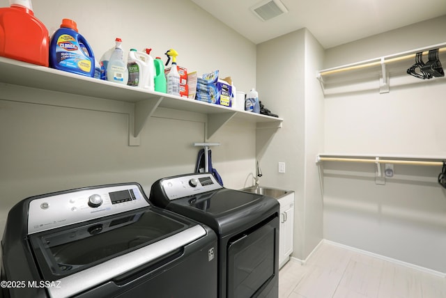 washroom featuring sink, cabinets, and washing machine and clothes dryer