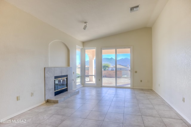 unfurnished living room with a mountain view, light tile patterned floors, lofted ceiling, and a fireplace