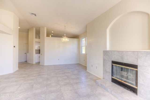 unfurnished living room featuring a tile fireplace and a notable chandelier