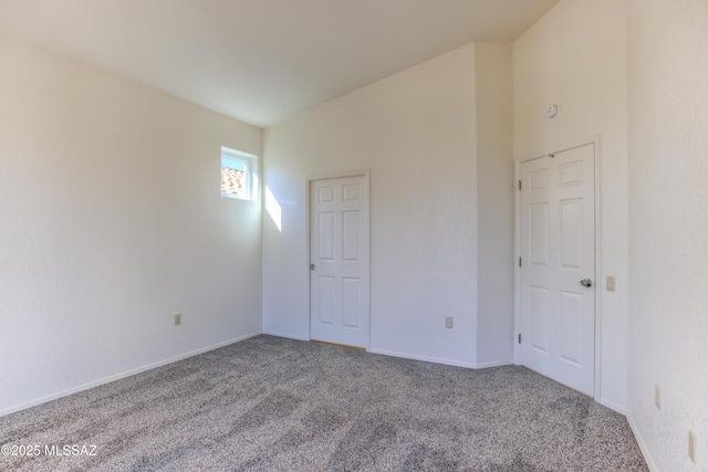 carpeted empty room with vaulted ceiling