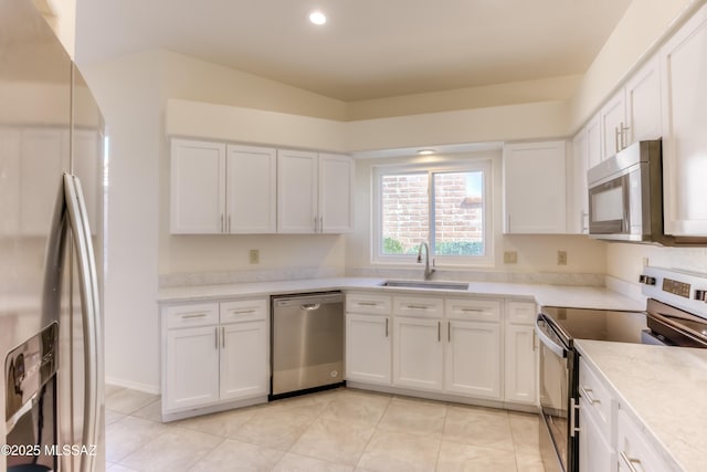 kitchen with sink, stainless steel appliances, white cabinetry, and light stone countertops