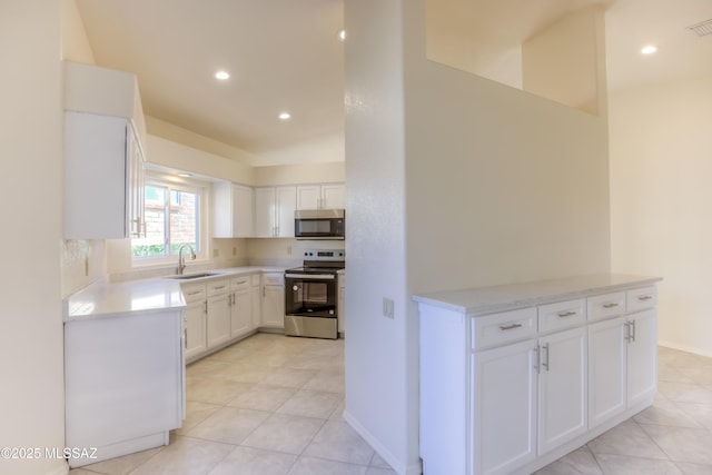 kitchen with sink, white cabinets, light tile patterned floors, and appliances with stainless steel finishes