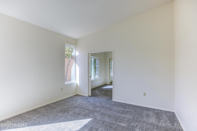 carpeted empty room with lofted ceiling