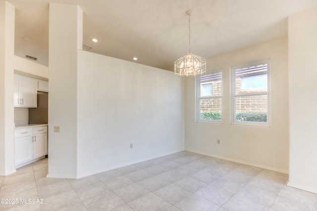 spare room featuring a notable chandelier and light tile patterned floors