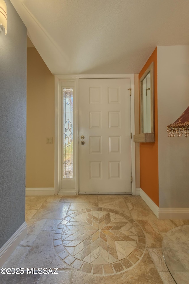 entryway featuring stone finish floor and baseboards