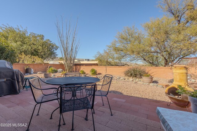 view of patio featuring outdoor dining space, a fenced backyard, and a grill