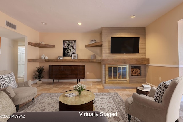 living room featuring a fireplace, stone tile floors, recessed lighting, visible vents, and baseboards