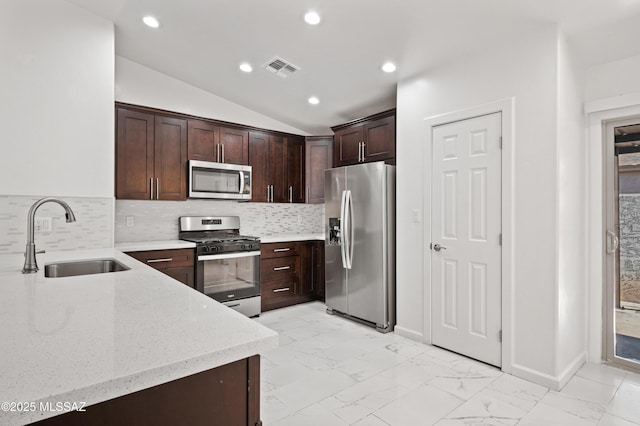 kitchen with lofted ceiling, sink, dark brown cabinets, appliances with stainless steel finishes, and light stone countertops