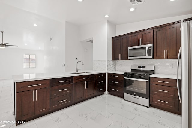 kitchen with appliances with stainless steel finishes, sink, backsplash, and kitchen peninsula