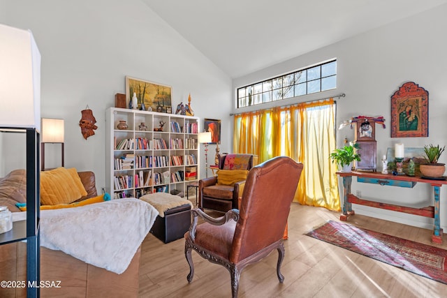 sitting room with high vaulted ceiling and light hardwood / wood-style flooring