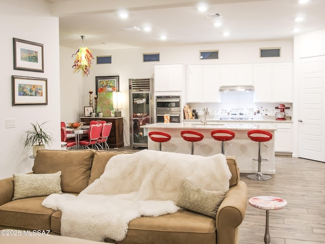 living room featuring sink and light hardwood / wood-style flooring