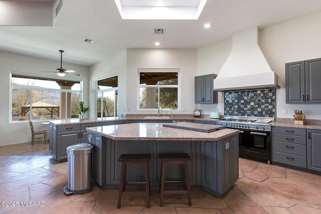 kitchen with premium range hood, light stone countertops, a center island, and double oven range