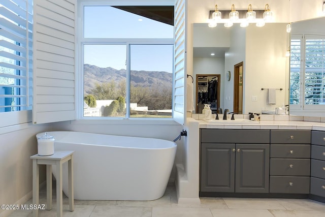 bathroom featuring a bathing tub, a mountain view, a wealth of natural light, and vanity