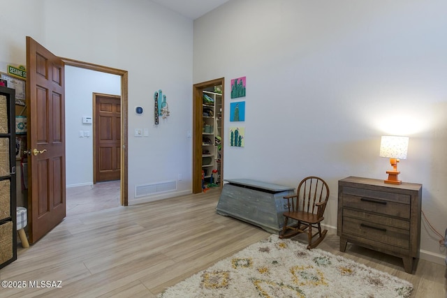 sitting room with a high ceiling and light hardwood / wood-style floors