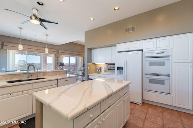 kitchen with white appliances, visible vents, a sink, and white cabinets