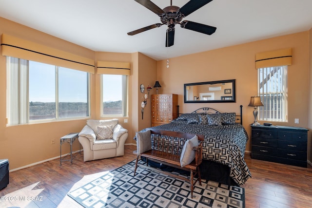 bedroom with ceiling fan, multiple windows, wood finished floors, and baseboards