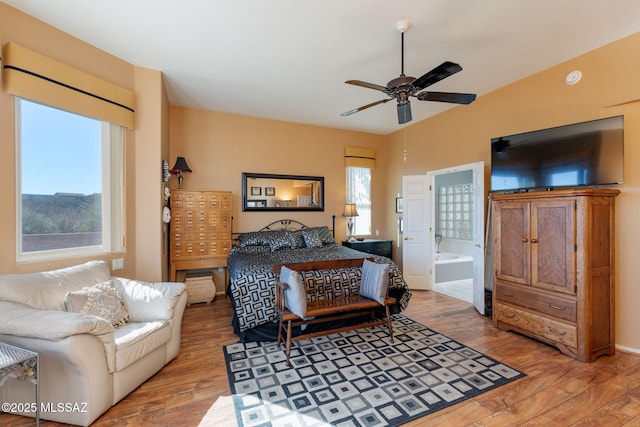 bedroom with ensuite bath, multiple windows, and wood finished floors