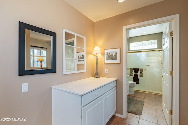 bathroom with tile patterned flooring, toilet, vanity, baseboards, and a shower stall