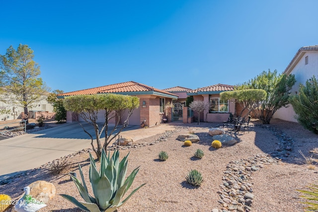 mediterranean / spanish home with an attached garage, fence, a tiled roof, concrete driveway, and stucco siding