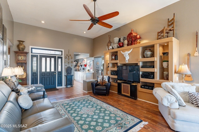 living area featuring recessed lighting, wood finished floors, a towering ceiling, and a ceiling fan