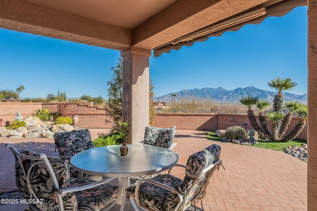 view of patio / terrace with a fenced backyard, a mountain view, and outdoor dining space