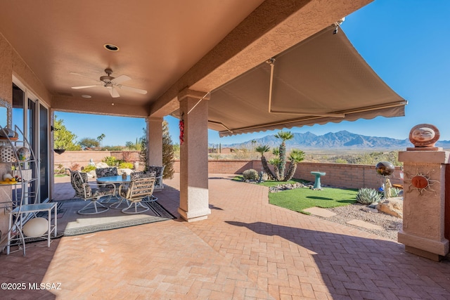 view of patio with ceiling fan, a fenced backyard, a mountain view, and outdoor dining area