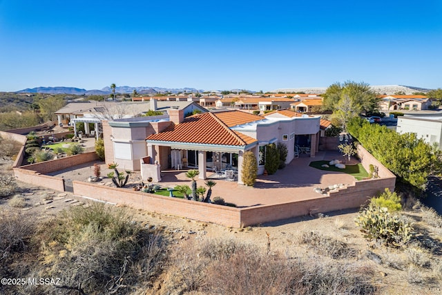 rear view of house featuring stucco siding, a patio, a fenced backyard, and a mountain view