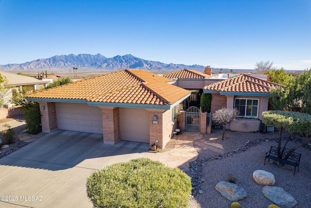 view of front of house featuring a mountain view, concrete driveway, a tile roof, and a gate