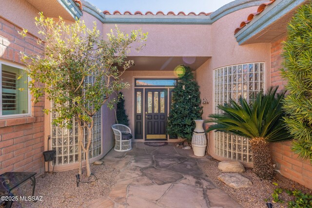 entrance to property with french doors, a patio area, and stucco siding