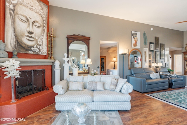 living room with a fireplace with raised hearth and wood finished floors