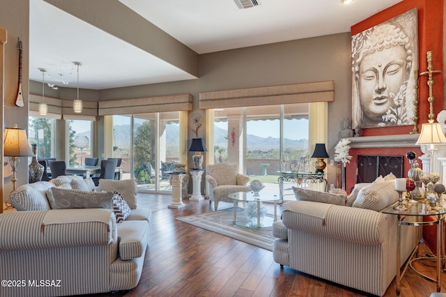 living area featuring a fireplace, a mountain view, visible vents, and wood finished floors