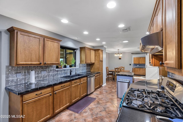 kitchen with sink, range hood, stainless steel appliances, decorative backsplash, and decorative light fixtures