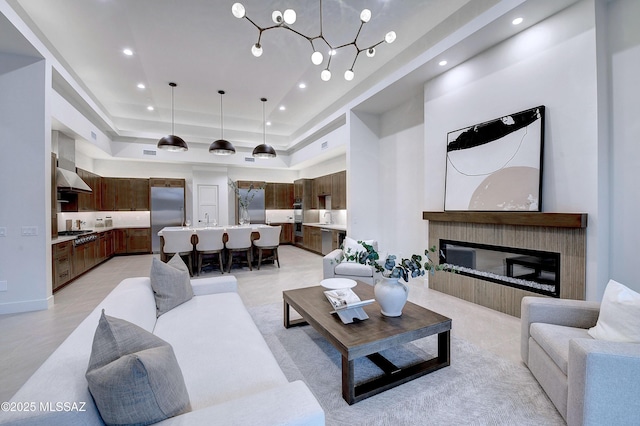 living room with a towering ceiling, a chandelier, and a raised ceiling